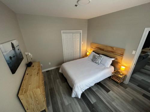 a bedroom with a white bed and a wooden floor at Premium 2-bed Condo Uptown Saint John Parking Coffee Location in Saint John