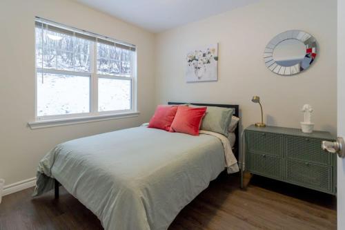 Schlafzimmer mit einem Bett mit roten Kissen und einem Fenster in der Unterkunft New 2BD Condo, UNB, Hospital, Golf, Patio Coffee in Saint John