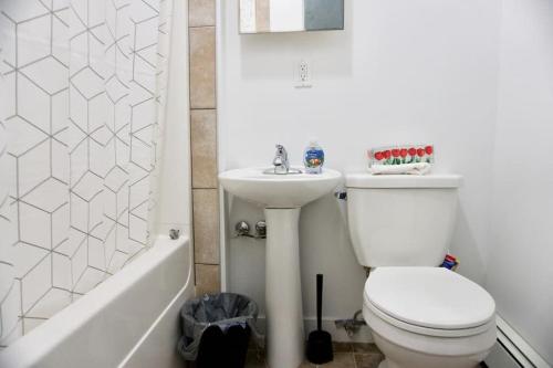 a bathroom with a toilet and a sink and a tub at Amazing DT Apartment w Parking Location Coffee in Moose Jaw