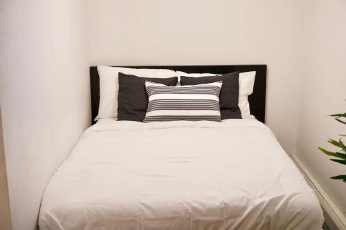 uma cama branca com uma cabeceira preta num quarto em Cozy Studio Downtown Parking Coffee Location em Moose Jaw