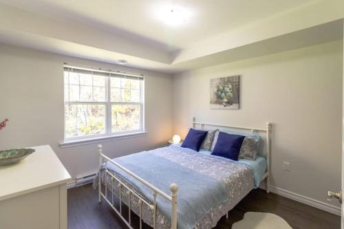 a bedroom with a bed with blue pillows and a window at Brand new Gorgeous Condo Near UNB & Hospital Coffee Parking 202 in Saint John