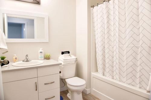 La salle de bains blanche est pourvue de toilettes et d'un rideau de douche. dans l'établissement Premium Modern Condo Top Location 2Bed, à Winnipeg