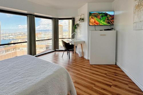 a bedroom with a bed and a desk with a television at 1BR Ocean Sunset View With Parking in Honolulu