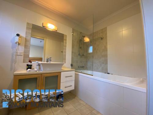a bathroom with a sink and a tub and a mirror at Tomarlin Views 1 in Thredbo