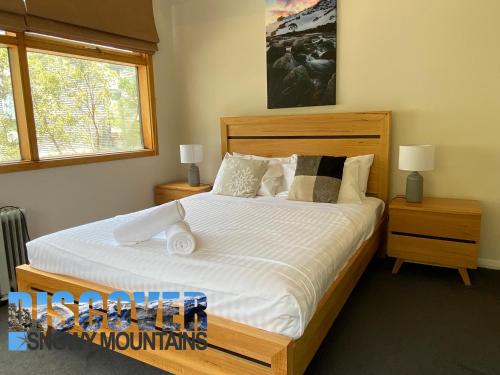 a bedroom with a large bed with white sheets and pillows at Tomarlin Views 1 in Thredbo