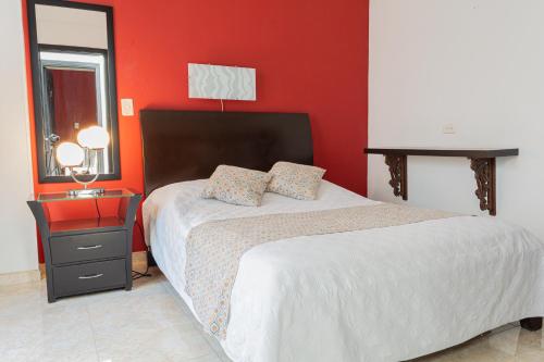 a bedroom with a bed and a red wall at Hotel Victoria in Chinchiná