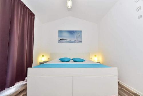 1 dormitorio con cama blanca y almohadas azules en Apartments with a parking space Vir - 22542, en Vir