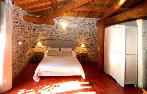 - une chambre avec un lit blanc dans une pièce dotée de plafonds en bois dans l'établissement Chambres lou castel, à Malves