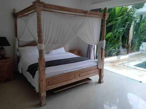 a canopy bed in a bedroom with a window at UMARA villa bali x villa aydin kerobokan bali in Seminyak