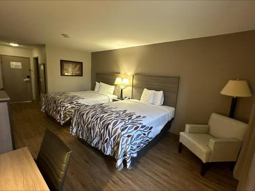 um quarto de hotel com duas camas e uma cadeira em Red Roof Inn Gurnee - Waukegan em Waukegan