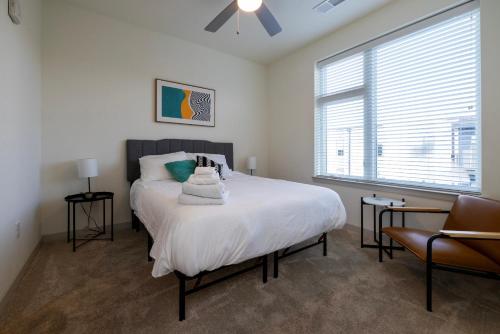 um quarto com uma cama com lençóis brancos e uma janela em Modern Nulu 2BR CozySuites 01 em Louisville
