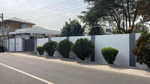 a white fence with trees on the side of a road at NBA PLUSH APARTMENT - NSROMA in Accra