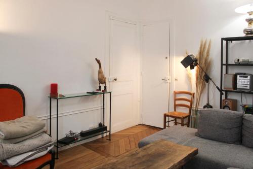 een woonkamer met een bank en een vogel op een plank bij Spacious apartment - near Palais Garnier in Parijs