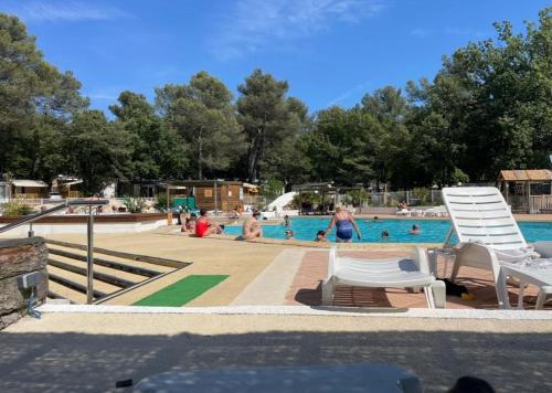 une piscine avec des gens jouant dans l'eau dans l'établissement Bungalow confortable à Nans-les-Pins avec piscine partagée, à Nans-les-Pins