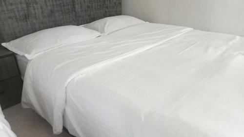 a large white bed with white sheets and pillows at Adamia Roomstay in Dungun 01 in Dungun
