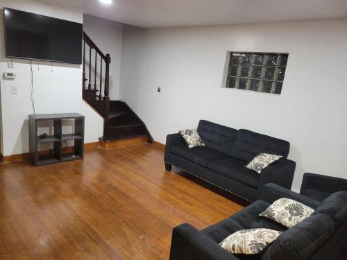 ein Wohnzimmer mit einem schwarzen Sofa und einem TV in der Unterkunft Cozy home in Washington Heights in Chicago