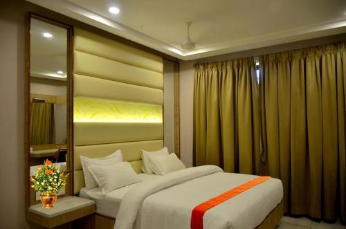 a bedroom with two beds and a mirror at Dwarka Palace Luxury Hotel in Madurai