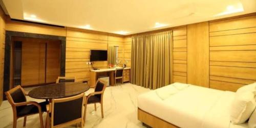 a bedroom with a bed and a table and a desk at Dwarka Palace Luxury Hotel in Madurai