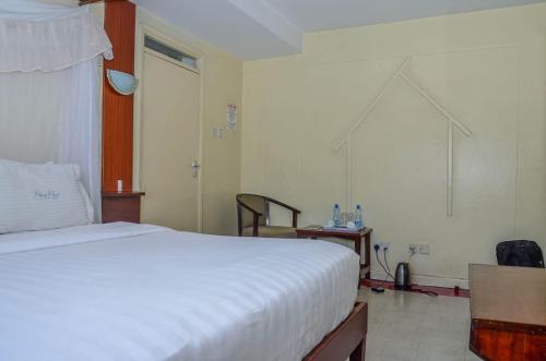 ein Schlafzimmer mit einem großen weißen Bett in einem Zimmer in der Unterkunft Blue Hut Hotel in Nairobi