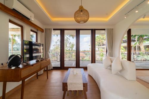 a living room with a white couch and a tv at Om Ham Retreat and Resort in Ubud