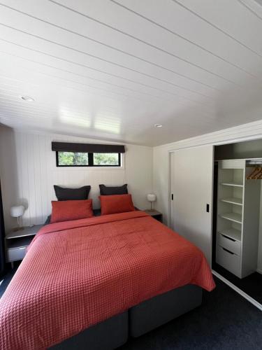 a bedroom with a large bed with red pillows at Pond Road Park - Raglan in Raglan
