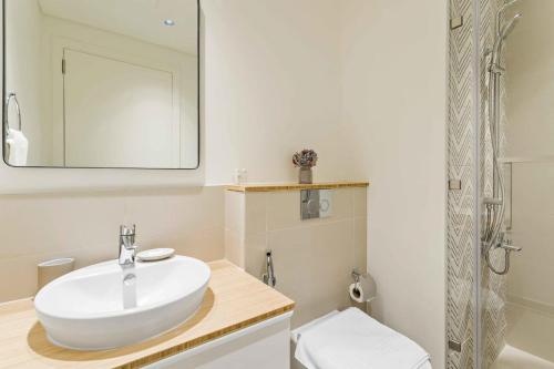 uma casa de banho com um lavatório branco e um espelho. em Silkhaus 1BDR in Dubai Hills with pool access, very bright em Dubai