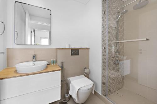 een badkamer met een toilet, een wastafel en een spiegel bij Silkhaus quiet neighborhood at Dubai Hills 1BDR in Dubai