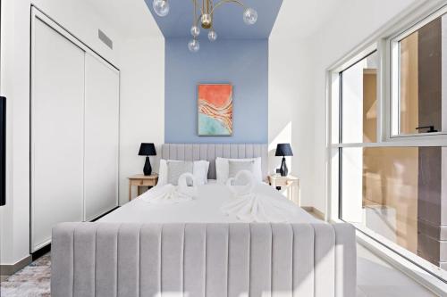 een slaapkamer met een groot wit bed en blauwe muren bij Silkhaus at Dubai Hills Collective One bedroom in Dubai