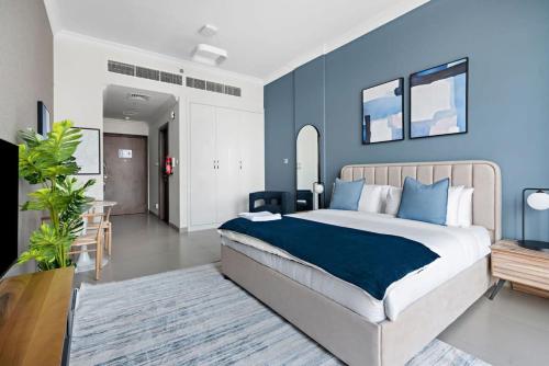 a bedroom with a large bed with blue walls at Silkhaus new studio in Art Gardens pool access in Dubai