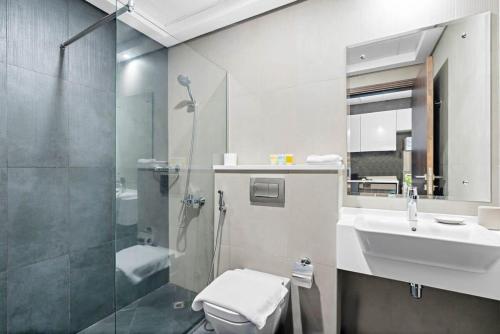 uma casa de banho com um chuveiro, um WC e um lavatório. em Silkhaus new studio in Art Gardens pool access no Dubai