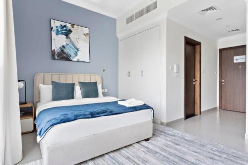 um quarto com uma cama king-size e paredes azuis em Silkhaus luxurious studio in Art Gardens with gym access em Dubai