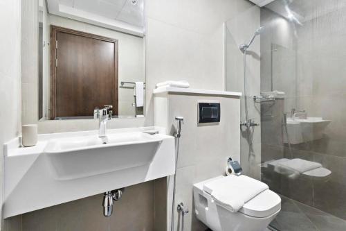 uma casa de banho com um lavatório, um WC e um chuveiro em Silkhaus luxurious studio in Art Gardens with gym access em Dubai
