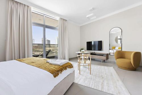 sypialnia z łóżkiem, biurkiem i telewizorem w obiekcie Silkhaus spacious studio in Art Gardens with gym & pool access w Dubaju