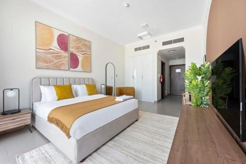1 dormitorio con 1 cama grande y TV en Silkhaus exquisite studio in Art Gardens with gym access, en Dubái