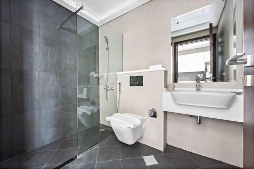 uma casa de banho com um WC, um lavatório e um chuveiro em Chic Studio in Art Gardens Modern Living no Dubai