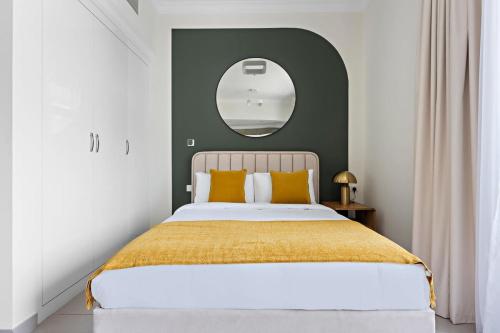 a bedroom with a large bed with a round mirror at Silkhaus modern studio in Art Gardens in-house kitchen in Dubai
