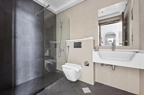 La salle de bains est pourvue de toilettes, d'un lavabo et d'une douche. dans l'établissement Silkhaus modern studio in Art Gardens in-house kitchen, à Dubaï