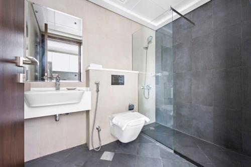 ein Bad mit einem WC, einem Waschbecken und einer Dusche in der Unterkunft Silkhaus new studio in Art Gardens gym & pool access in Dubai