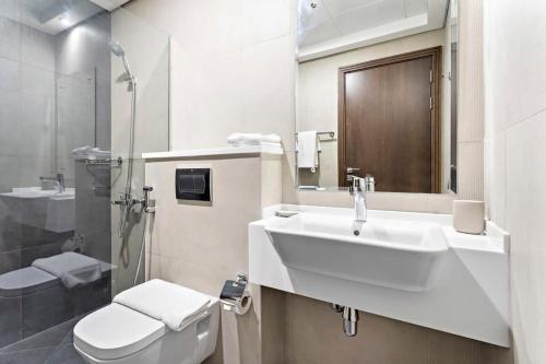 biała łazienka z umywalką i toaletą w obiekcie Silkhaus aesthetic studio in Art Gardens with gym & pool access w Dubaju