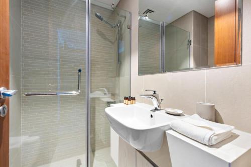 y baño con lavabo y ducha acristalada. en Silkhaus New 1 BDR |Near Reem Mall |Al Reem Island en Abu Dabi