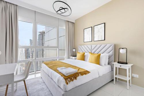 a white bedroom with a desk and a bed with yellow pillows at Silkhaus Luxurious 1 BDR Al Fay Park Nearby in Abu Dhabi