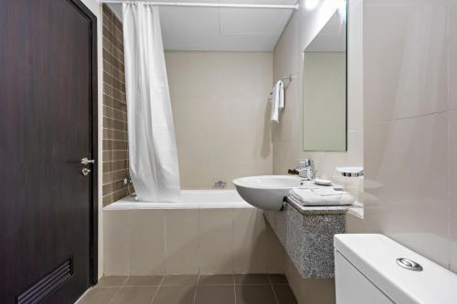 uma casa de banho branca com um lavatório e uma banheira em Silkhaus Spacious 1 BDR Al Fay Park Nearby em Abu Dhabi
