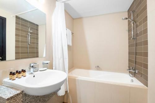 uma casa de banho com um lavatório e uma banheira e um lavatório em Silkhaus High Floor 1 BDR Al Fay Park Nearby em Abu Dhabi