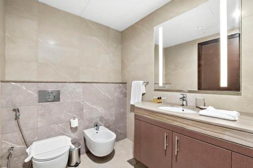 a bathroom with a toilet and a sink and a mirror at Silkhaus Spacious 2 BDR Reem Central Park Nearby in Abu Dhabi