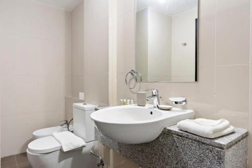 een witte badkamer met een wastafel en een toilet bij Silkhaus Modern 1 BDR Al Fay Park Nearby in Abu Dhabi