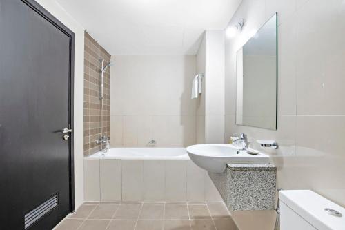 uma casa de banho branca com um lavatório e uma banheira em Silkhaus Large 1 BDR Al Fay Park Nearby em Abu Dhabi