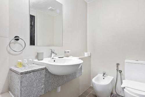 uma casa de banho branca com um lavatório e um WC em Silkhaus New 1 BDR Al Fay Park Nearby em Abu Dhabi