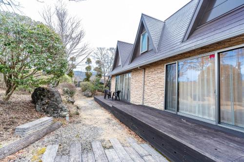 a house with two dogs sitting on a wooden porch at 完全貸切別荘 天然温泉 La Saison inn Kirishima 888 in Kirishima