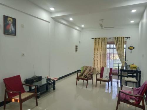 uma sala de estar com cadeiras, uma mesa e uma janela em STS Roomes / House em Batticaloa