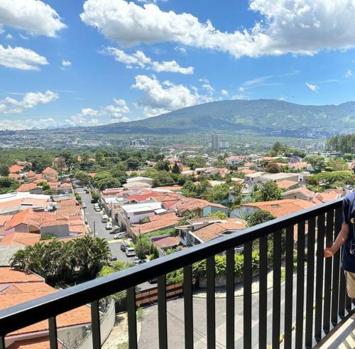 eine Person, die auf einem Balkon mit Blick auf eine Stadt steht in der Unterkunft Sunset 302 in Antiguo Cuscatlán